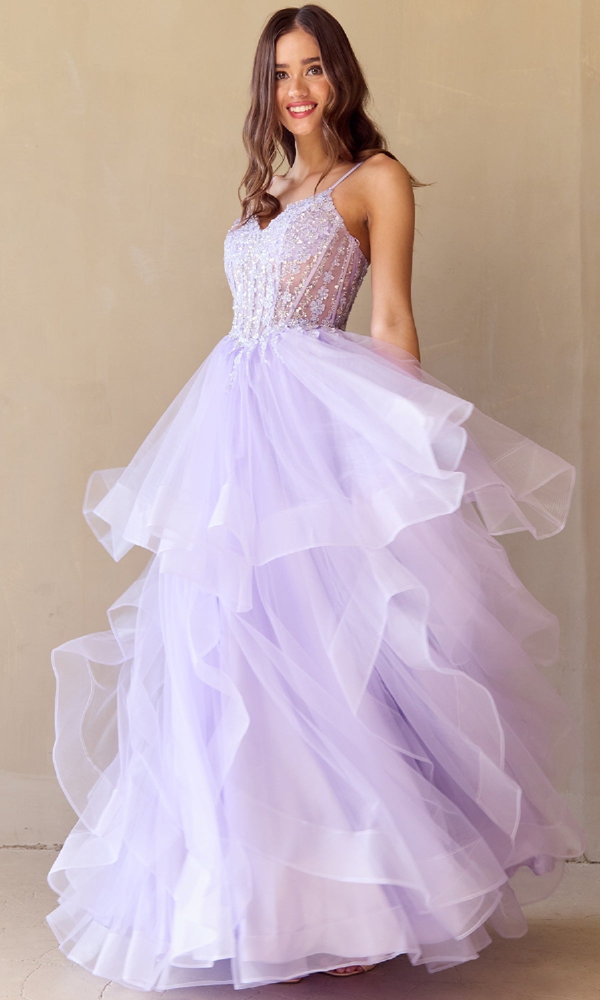 A woman models the Long Glitter Prom Ball Gown: Amelia Couture 5068, featuring a sleeveless lavender beaded bodice and layered tulle skirt, standing before a plain beige background.